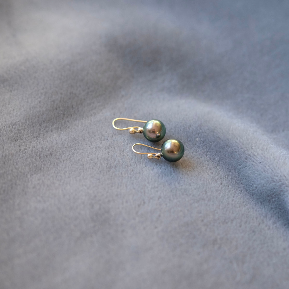 dark green-blue Tahitian pearls on a grey velvet t background