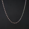A delicate chain necklace with alternating elongated oval links and small star-shaped links, shown against a solid black background.