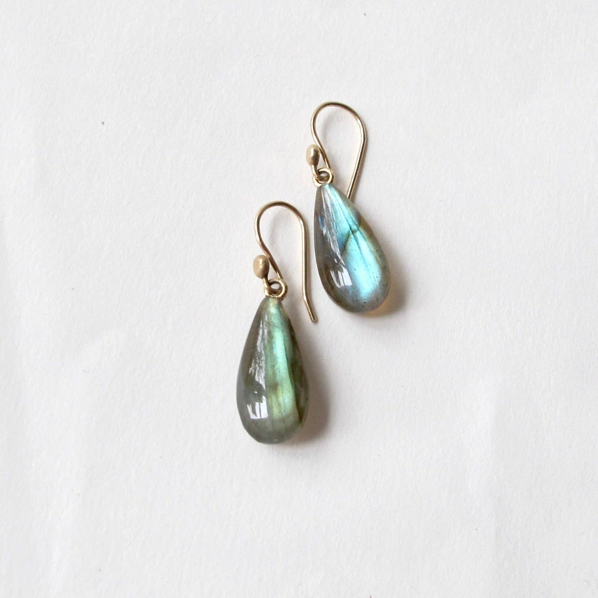 A pair of teardrop-shaped labradorite drop earrings with gold fishhook wires, displayed on a clean white background.