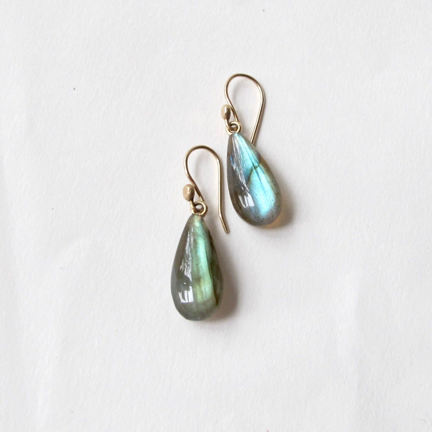 A pair of teardrop-shaped labradorite drop earrings with gold fishhook wires, displayed on a clean white background.