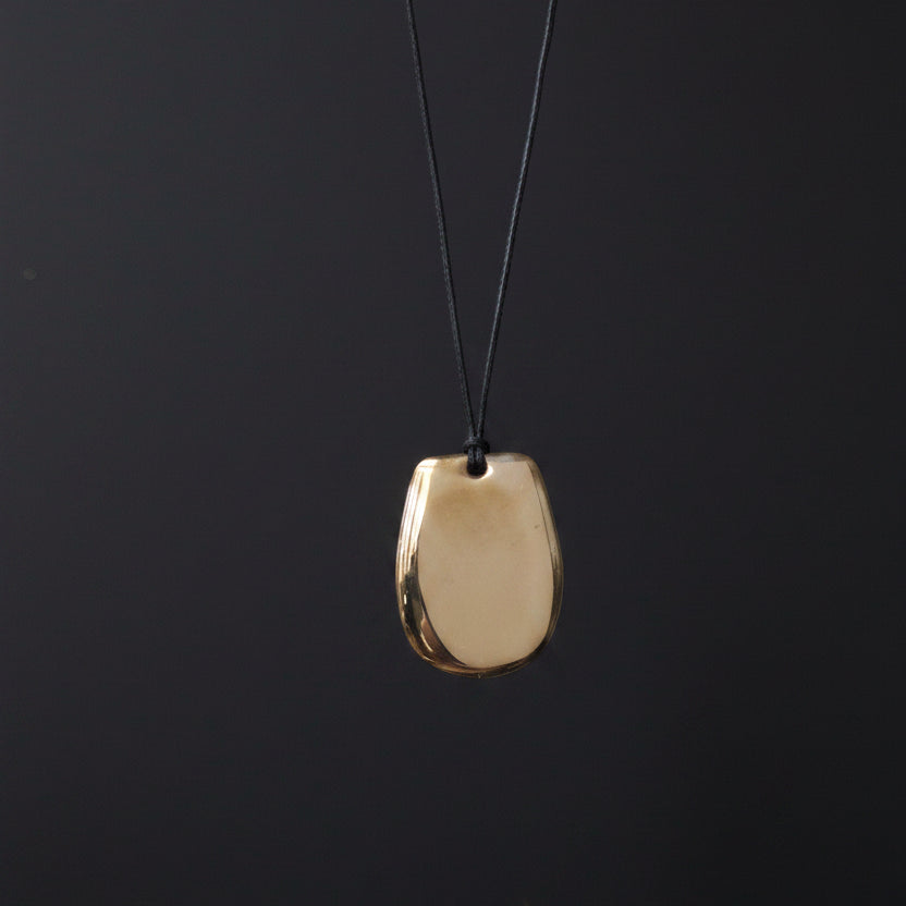 A minimalist metal pendant on a black background