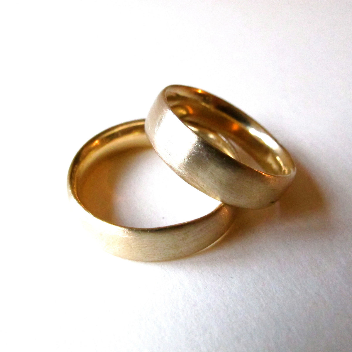 Two plain gold wedding bands photographed on a white background.