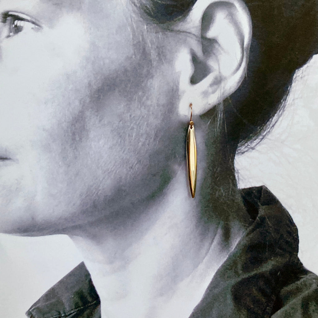 a black and white image of a person in profile with the simple gold earring on.