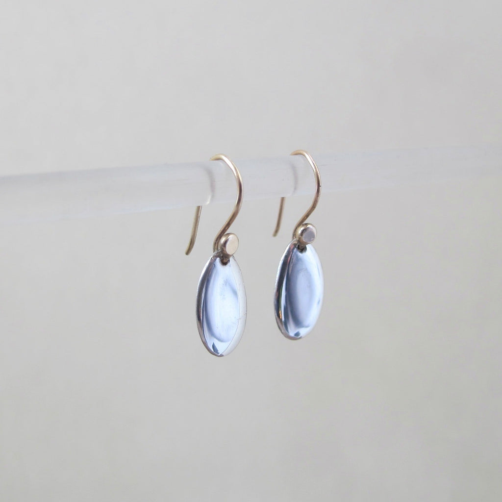 A pair of silver oval smooth polished earrings suspended from gold toned French wires.