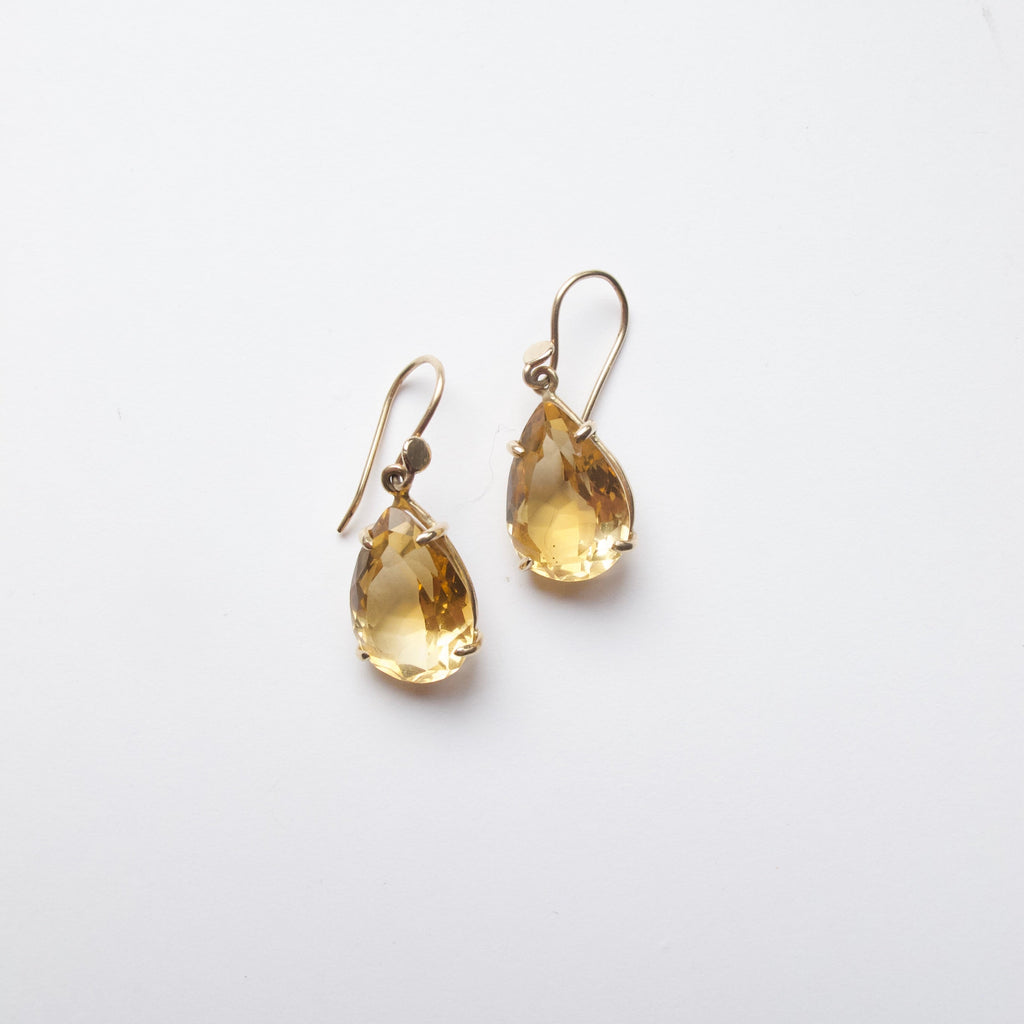 A pair of gold drop earrings featuring teardrop-shaped clear crystals, displayed on a clean white background.