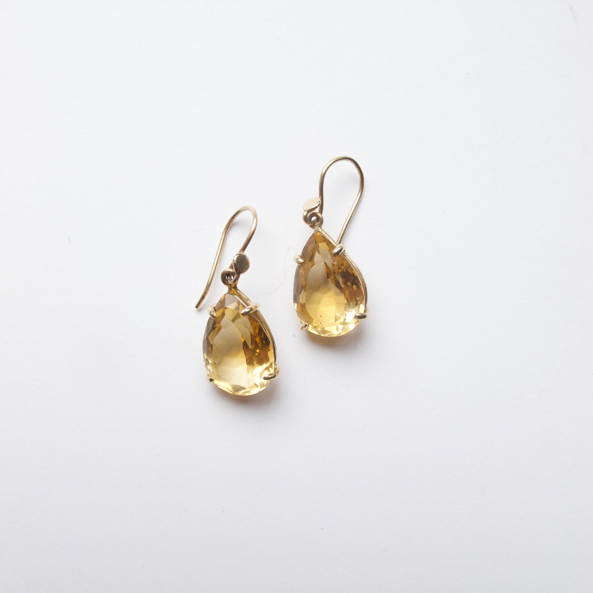 A pair of gold drop earrings featuring teardrop-shaped clear crystals, displayed on a clean white background.