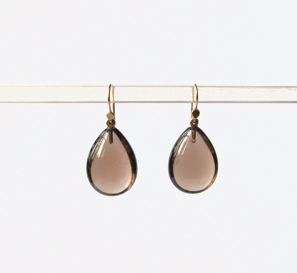 Teardrop-shaped smoky rose gold glass drop earrings hanging from gold-toned fishhook wires on a clear display bar against a white background.