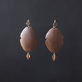 A pair of bohemian-style wooden dangle earrings with a warm medium-brown wood grain and small gold-toned metal accents, displayed against a dark charcoal background.