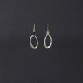 A pair of silver-toned open oval hoop earrings with fishhook backings, displayed against a dark charcoal background.